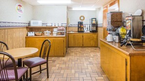 A small, cozy breakfast area with a wooden counter, a microwave, a coffee machine, and a clock on the wall. - Super 8 by Wyndham Nevada (Nevada)