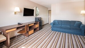 A hotel room with a bed, a desk with a chair, a television, and a blue sofa. - Super 8 by Wyndham Nevada (Nevada)