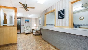 A hotel reception area with a herringbone-patterned floor, a reception desk, a large mirror, and a signboard with amenities. - Super 8 by Wyndham Nevada (Nevada)
