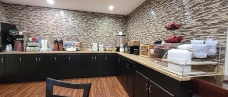 A kitchen with a stone backsplash, black cabinets, and a wooden countertop.