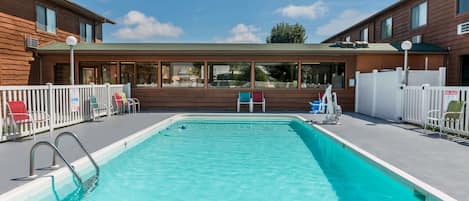 Una piscina al aire libre, sillones reclinables de piscina