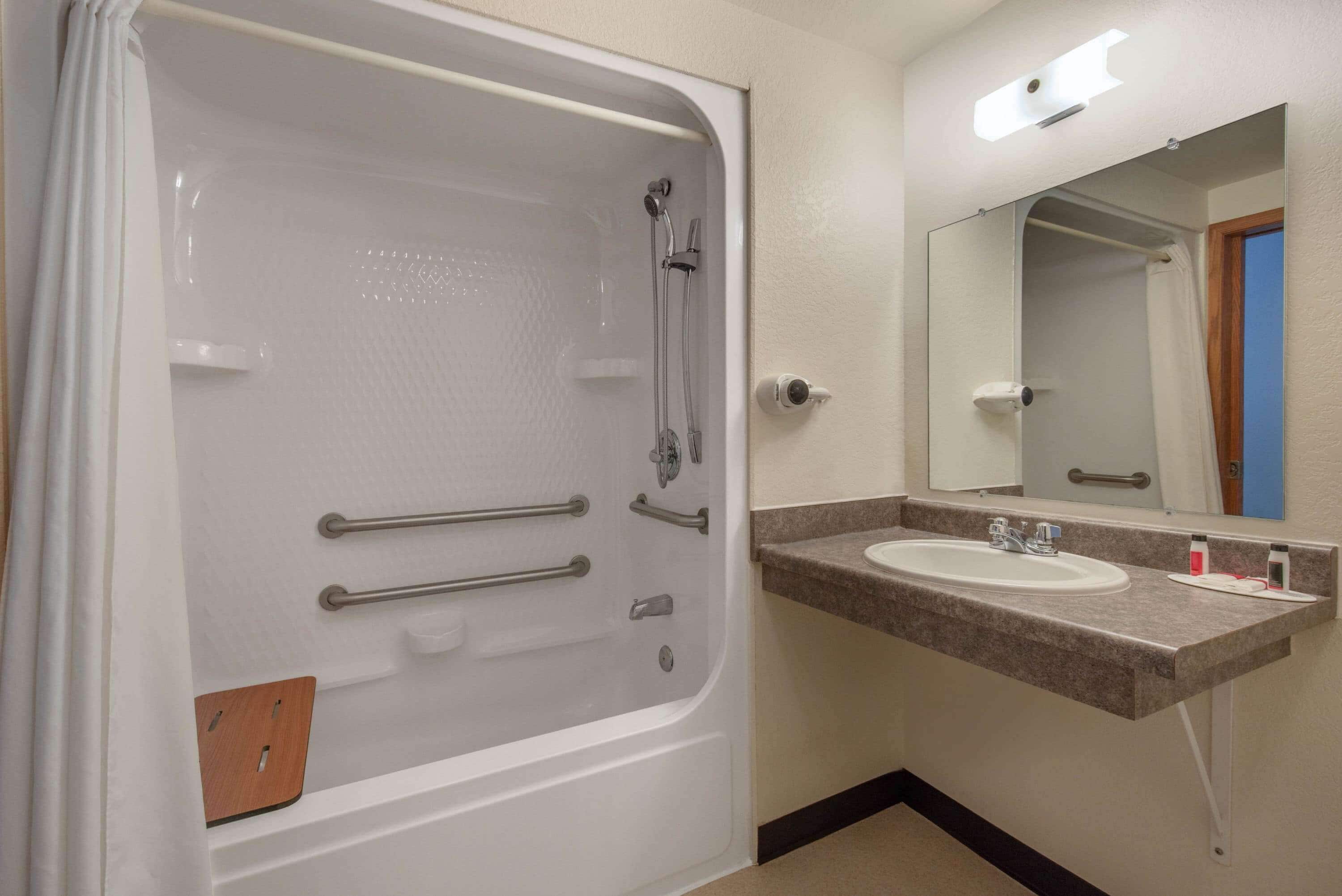 A bathroom with a bathtub, a sink, and a mirror.