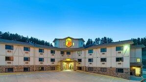 A Super 8 hotel with a central entrance, multiple windows, and a stone facade. - Super 8 by Wyndham Hill City/Mt Rushmore/ Area (Hill City)