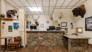 A reception area with a stone counter, wooden chairs, and mounted animal heads on the walls. - Super 8 by Wyndham Hill City/Mt Rushmore/ Area (Hill City)