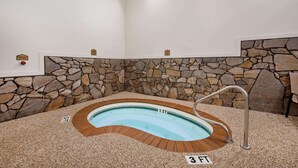 A hot tub with a stone wall backdrop, a metal ladder, and a 3 FT depth label. - Super 8 by Wyndham Hill City/Mt Rushmore/ Area (Hill City)