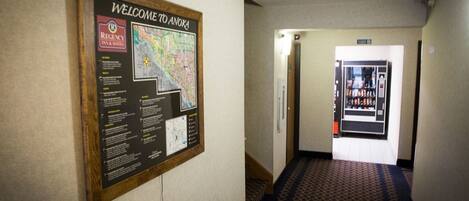 A hallway with a welcome sign and a vending machine.