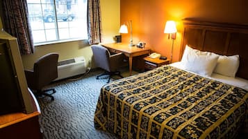 Une chambre d’hôtel avec un lit, un bureau, une chaise et une fenêtre avec des rideaux.