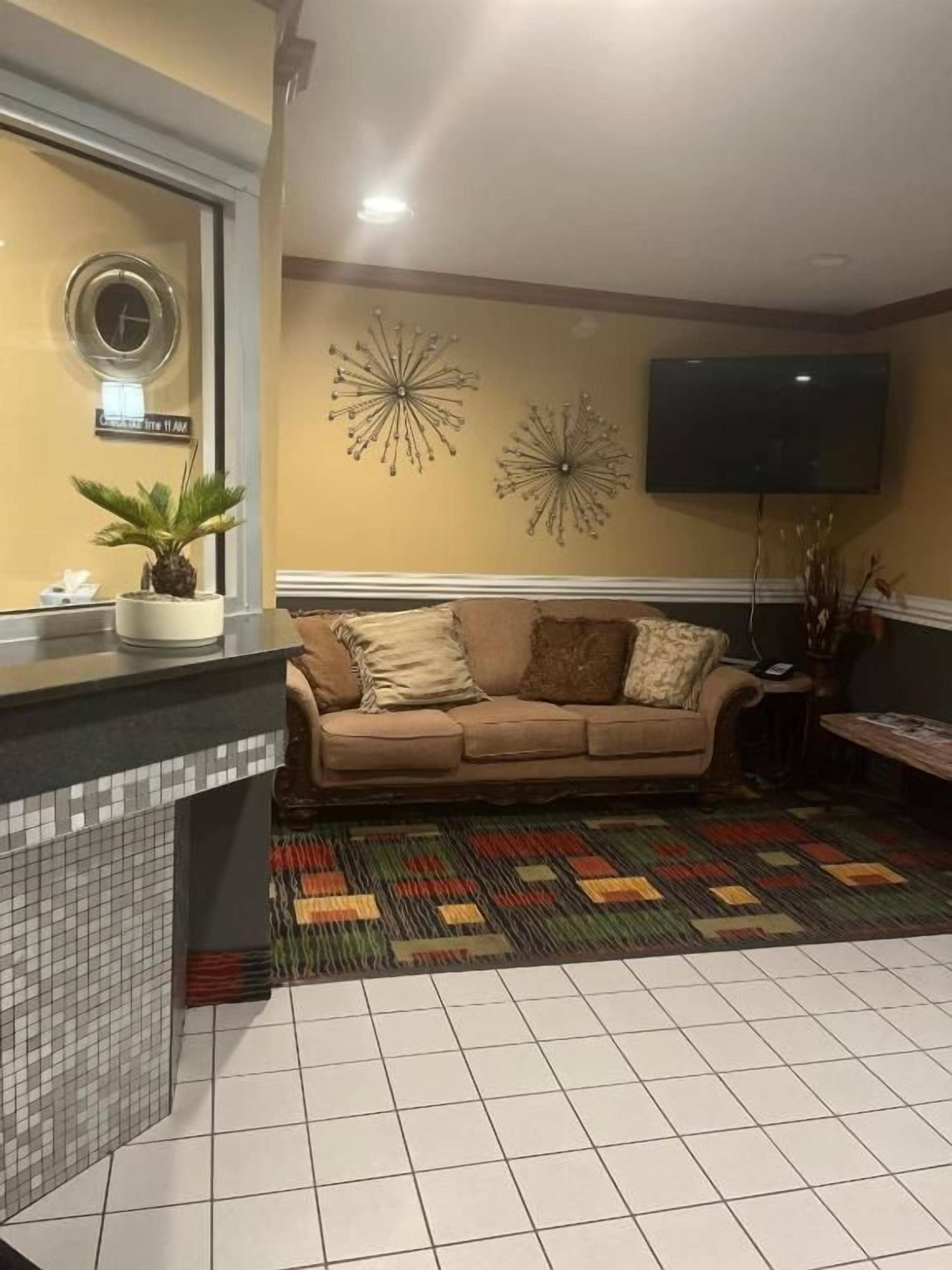 Un salon comprenant un canapé, un téléviseur, un tapis à motifs et un élément décoratif mural.