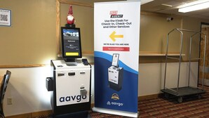 A kiosk with a screen for check-in/out services, a QR code sign, and a gnome decoration. - Magnuson Hotel Ironwood (Ironwood)