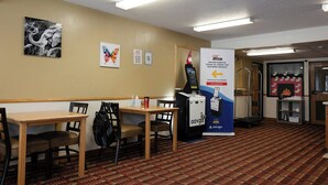 A hotel lobby with a kiosk, tables, chairs, and a fireplace. - Magnuson Hotel Ironwood (Ironwood)