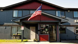 A building with a red and gray facade, an American flag, and a sign indicating employee parking. - Magnuson Hotel Ironwood (Ironwood)