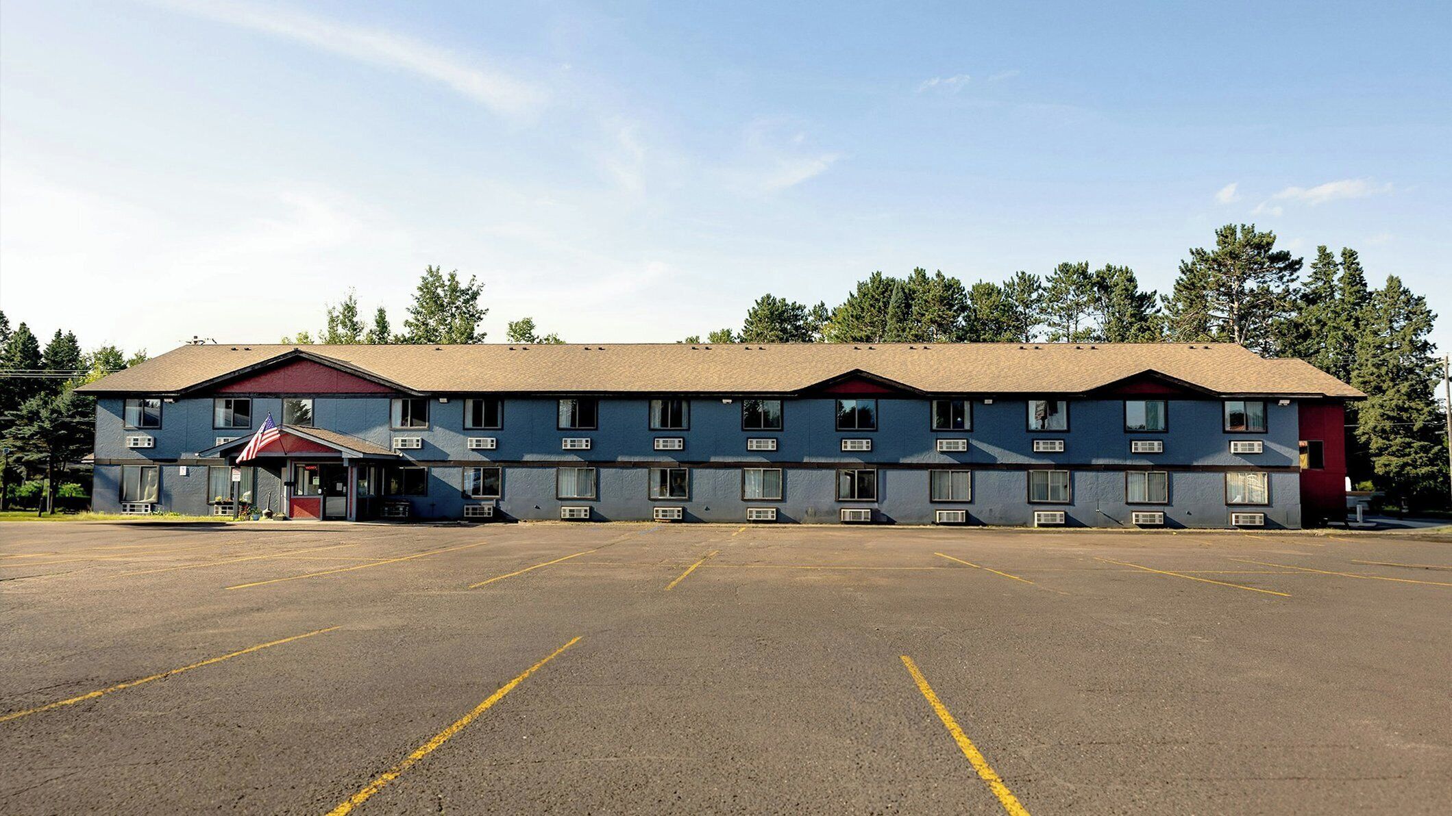 A multi-story motel with a large parking lot in front.