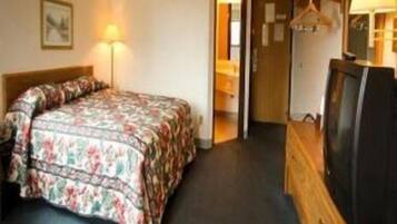 A hotel room with a bed, a television, and a lamp.