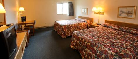 A hotel room with two beds, a desk, a television, and a window.