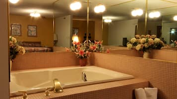 A bathroom with a large mirror, a bathtub, and a sink. There are towels and a basket of toiletries.