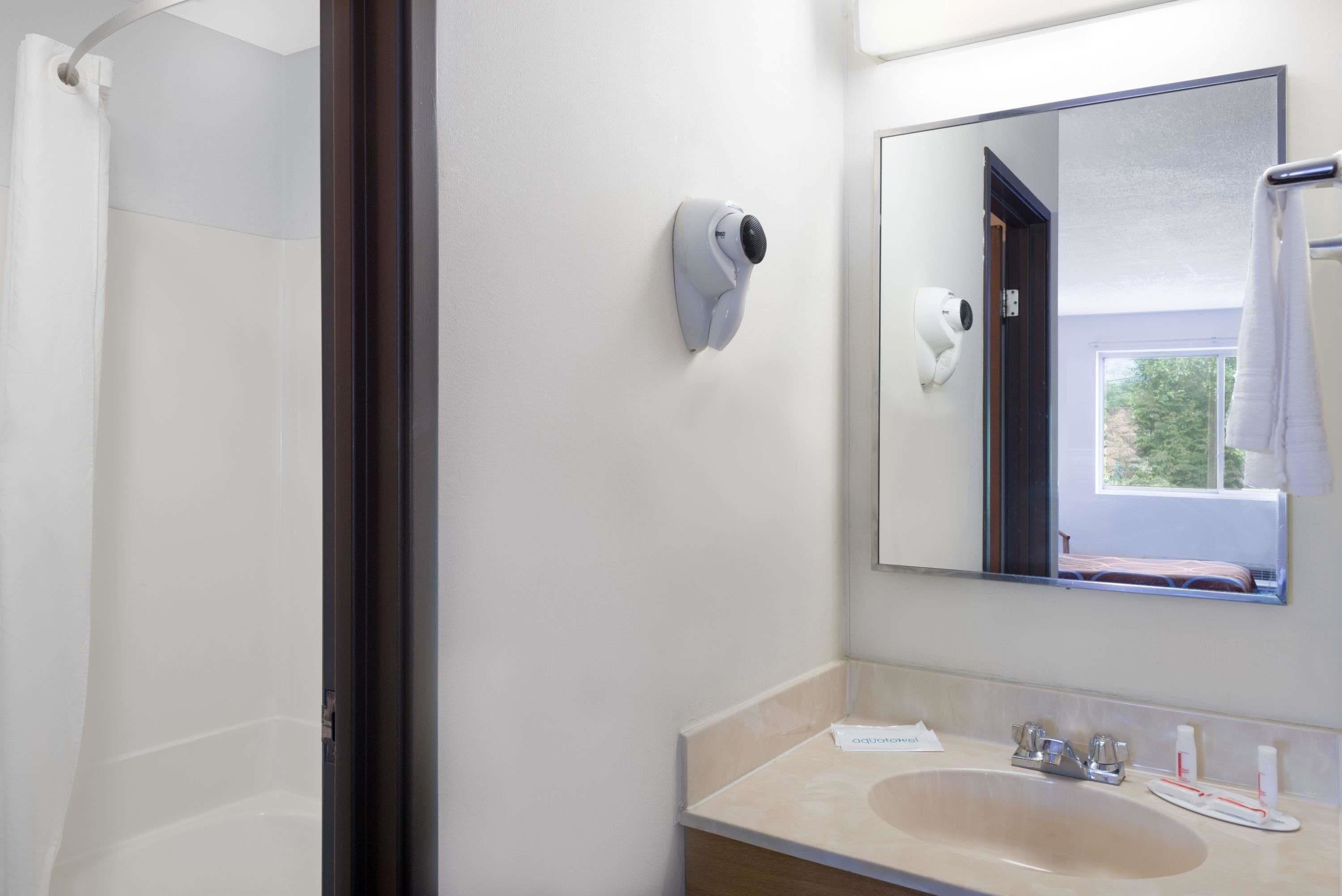 Un baño con ducha, lavabo, espejo y toallero.