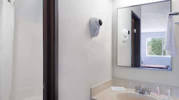 Un baño con ducha, lavabo, espejo y toallero.