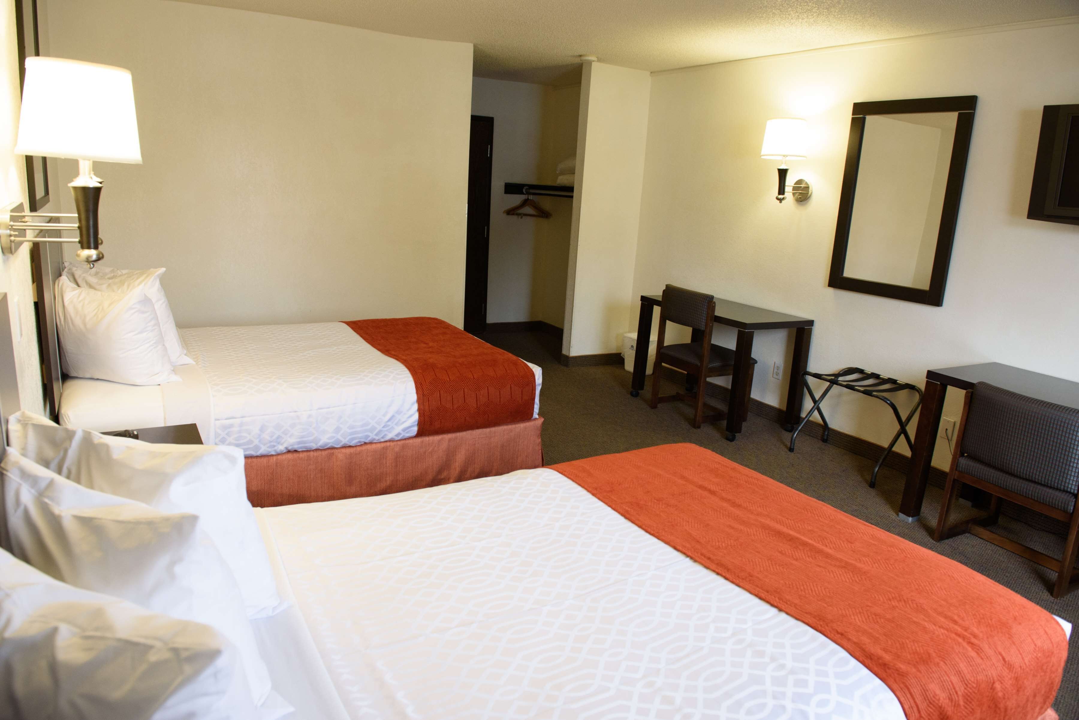 A hotel room with two beds, a desk, and a chair.