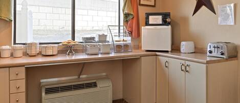 A kitchen with a window, a star decoration, a toaster, a microwave, and a small refrigerator.
