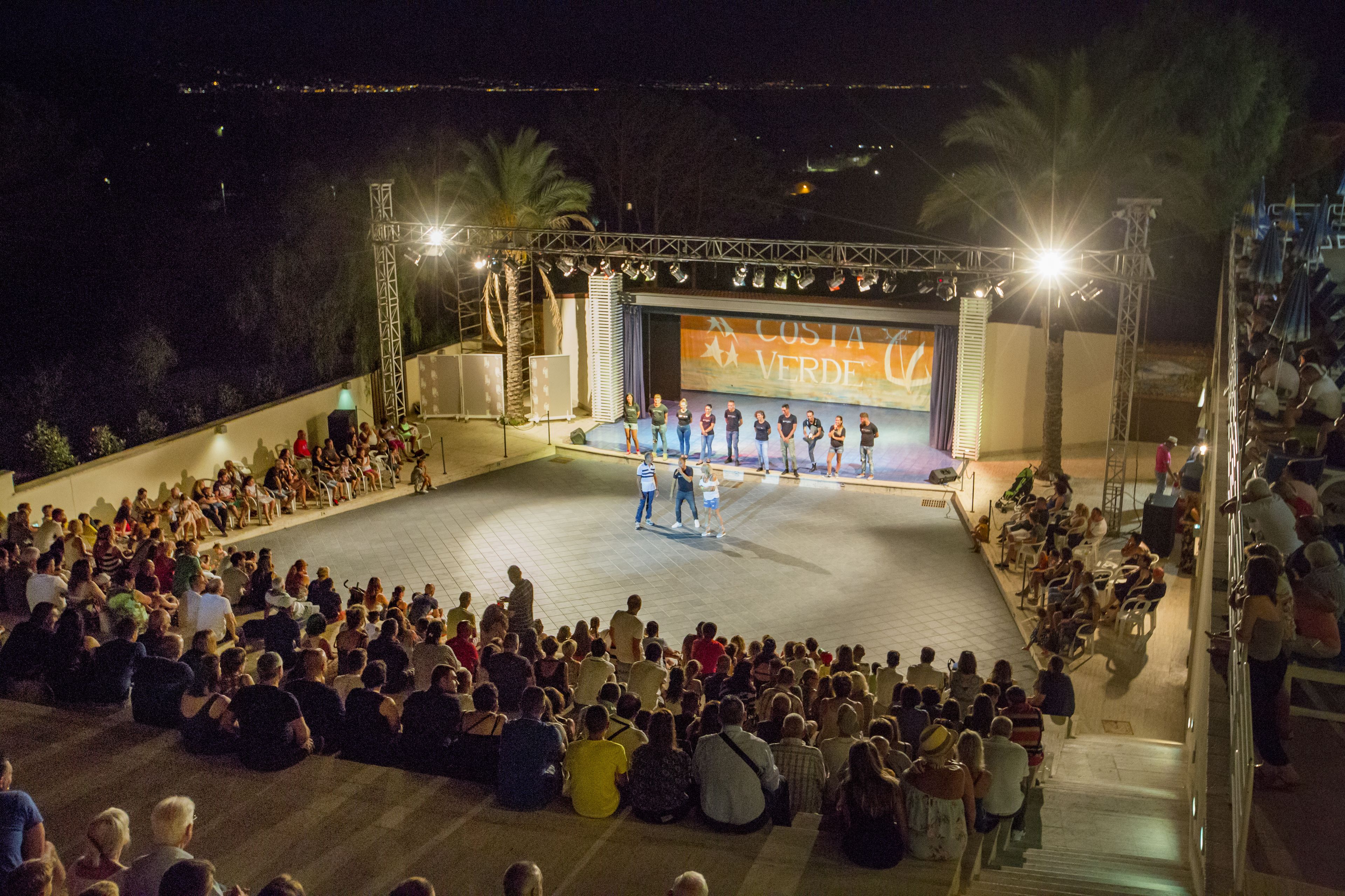 An outdoor stage with a crowd seated in front.