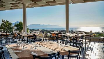 Zona pranzo all'aperto con tavoli apparecchiati per gli ospiti, con vista panoramica sul mare e sulle montagne.