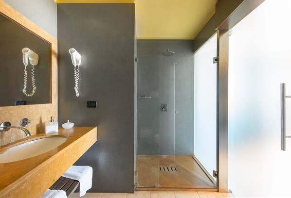 A modern bathroom with a large mirror, a sink, a hairdryer, and a shower. - Hotel Capo San Vito (San Vito Lo Capo)