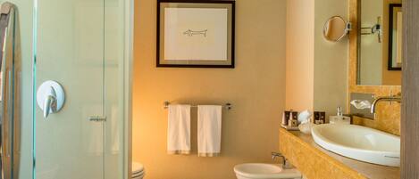 A modern bathroom with a glass shower, a toilet, a bidet, and a sink with a mirror.