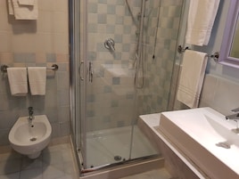 Une salle de bain moderne dotée d’une douche à parois de verre, d’un bidet et d’un lavabo.