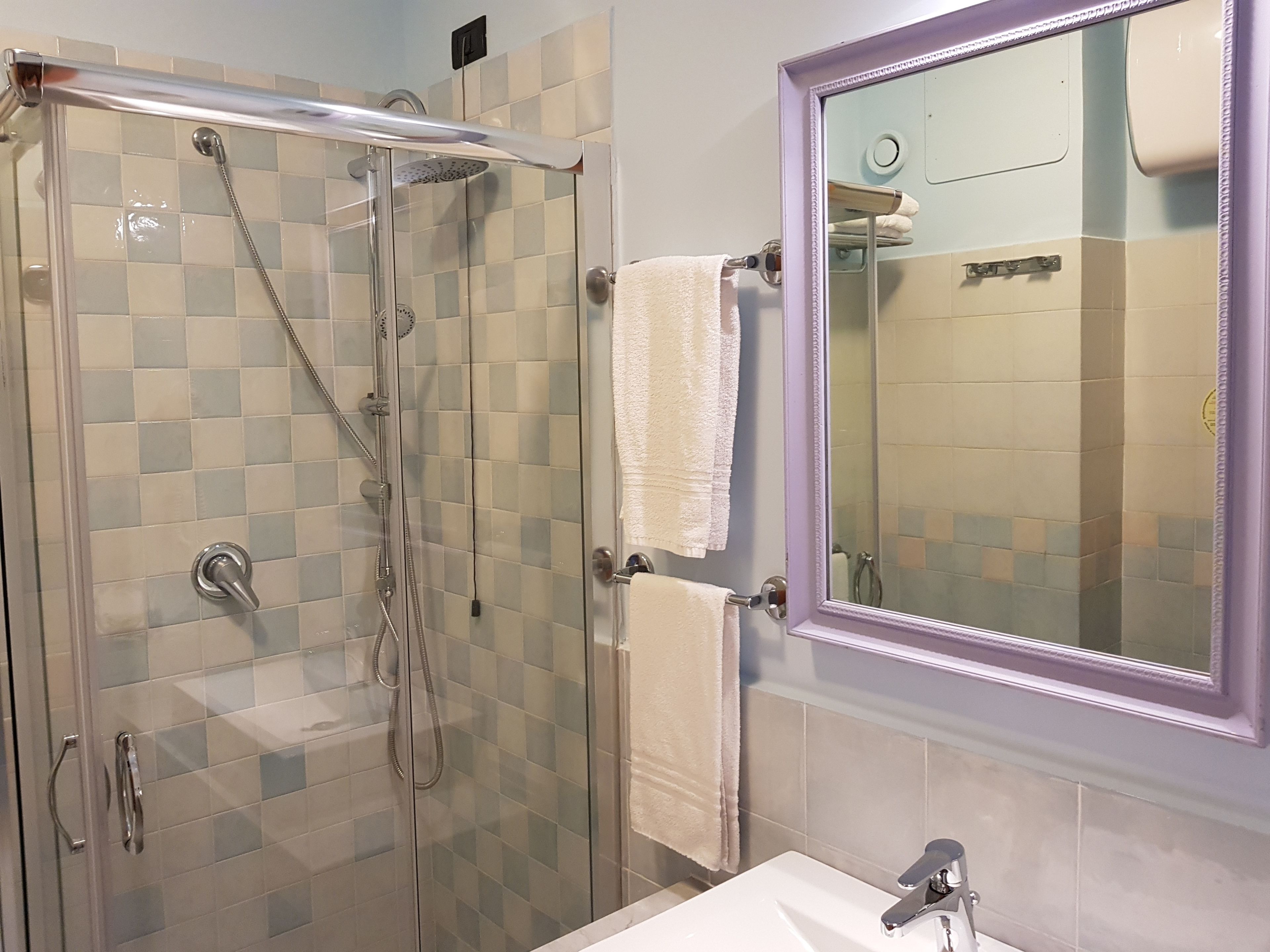 Un baño con ducha de vidrio, un lavamanos blanco y un espejo.