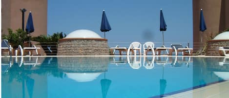 Piscine extérieure en saison, parasols, chaises longues