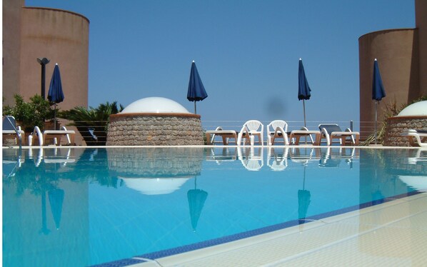 Una piscina al aire libre de temporada, sombrillas, tumbonas