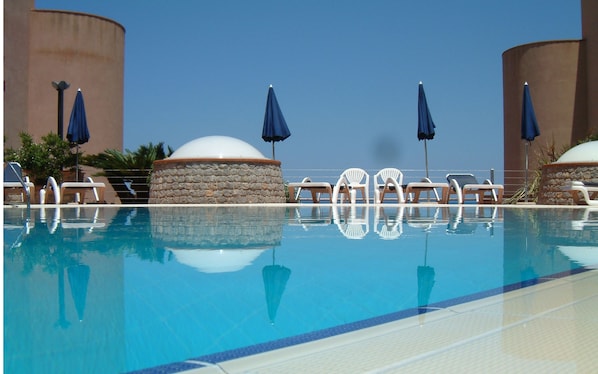 Una piscina al aire libre de temporada, sombrillas, tumbonas