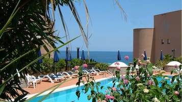 Relax by the oceanfront pool surrounded by lush greenery and lounge chairs.