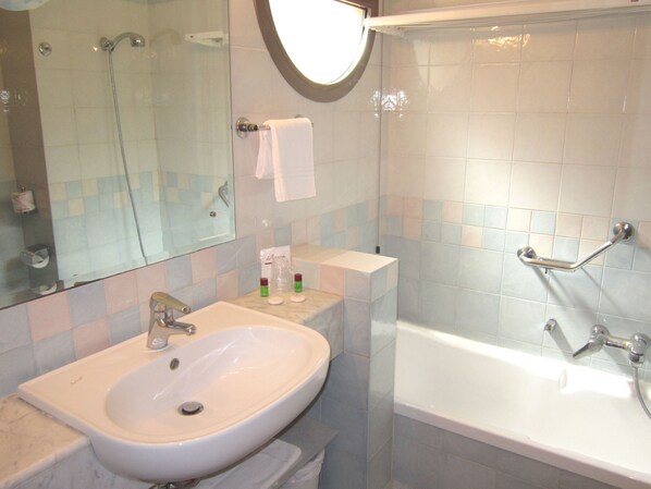 A bathroom with a sink, mirror, and bathtub.