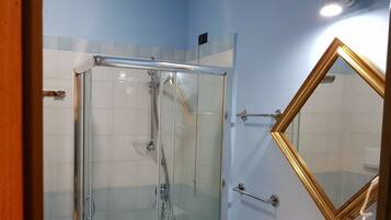 A glass-enclosed shower with a chrome handle and a towel rack.