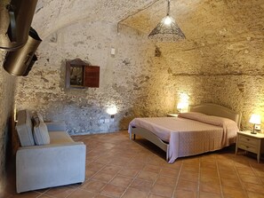 A rustic room with a bed, bedside lamps, a chair, and a hanging light fixture. - Residenza La Vigna (Parghelia)