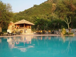 Una piscina al aire libre, sombrillas, sillones reclinables de piscina