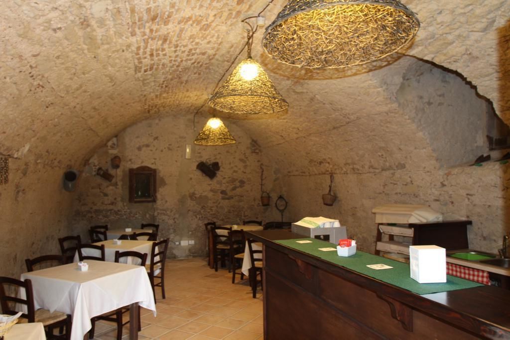 A rustic interior with stone walls, wooden tables, and hanging lamps.