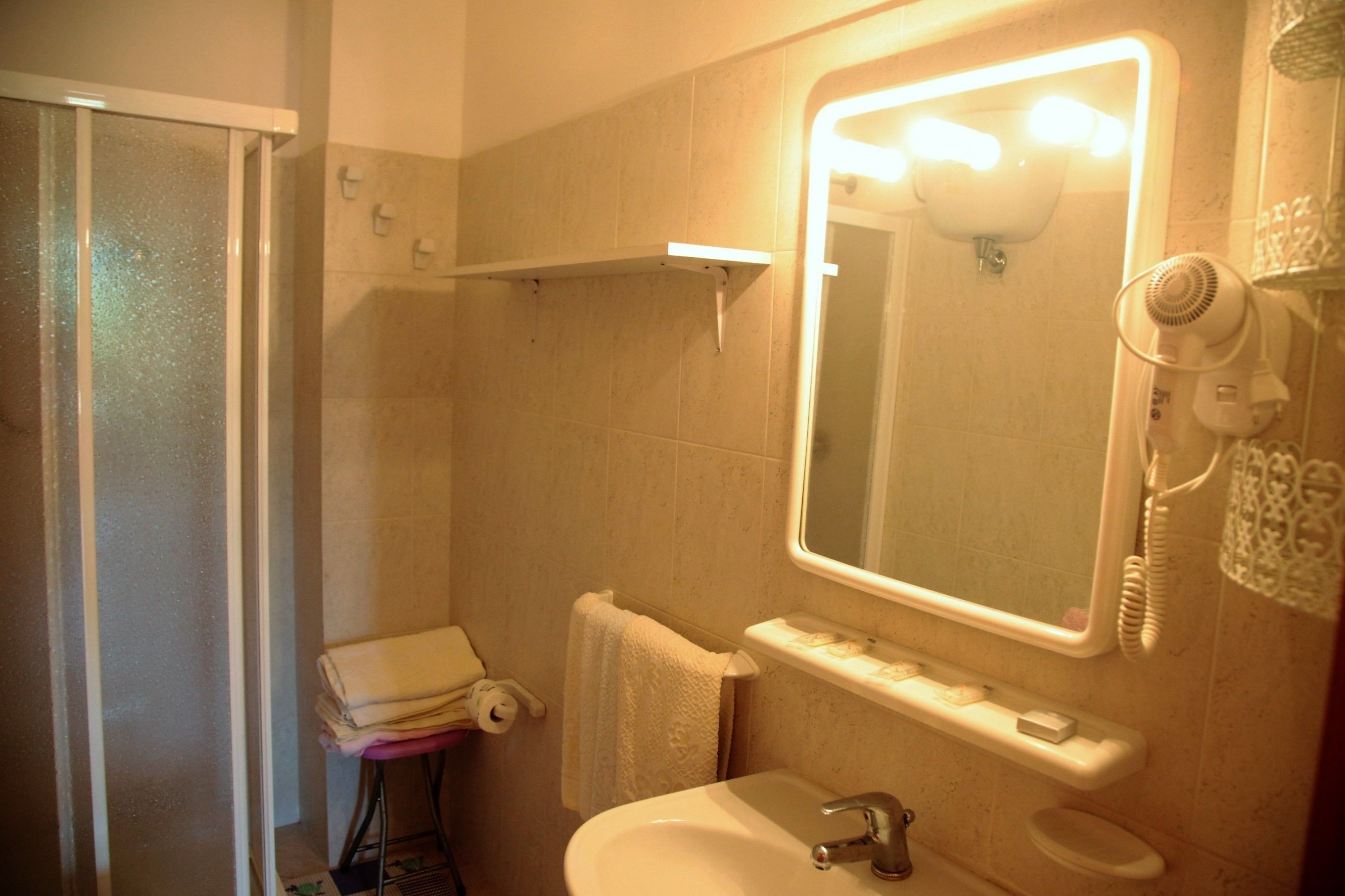 Une salle de bain équipée d’une douche, d’un lavabo, de toilettes, d’un miroir et d’un sèche-cheveux.