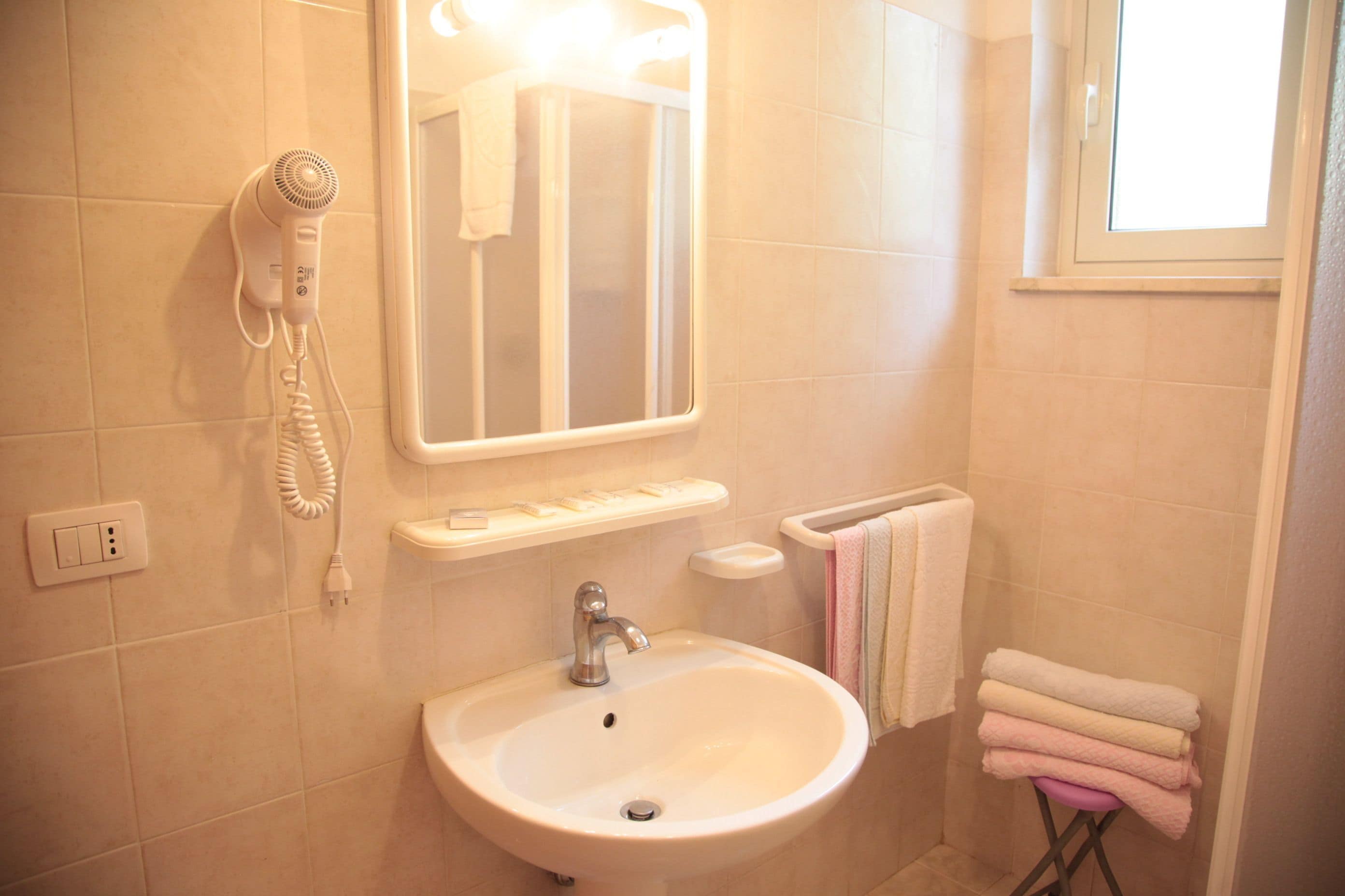 A bathroom with a sink, a mirror, a towel rack, and a hairdryer.