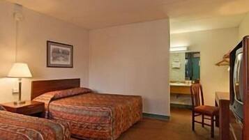 Een hotelkamer met twee bedden, een bureau, een stoel en een televisie.