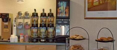 A breakfast bar with a coffee machine, bottles of olive oil, and a display of pastries.