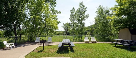 A picnic area with tables and chairs, surrounded by trees.