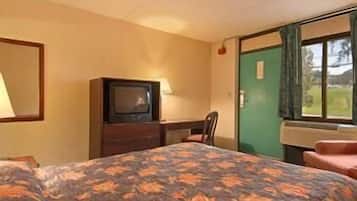 Ein Hotelzimmer mit Bett, Schreibtisch, Fernseher und einem Fenster mit Vorhängen.