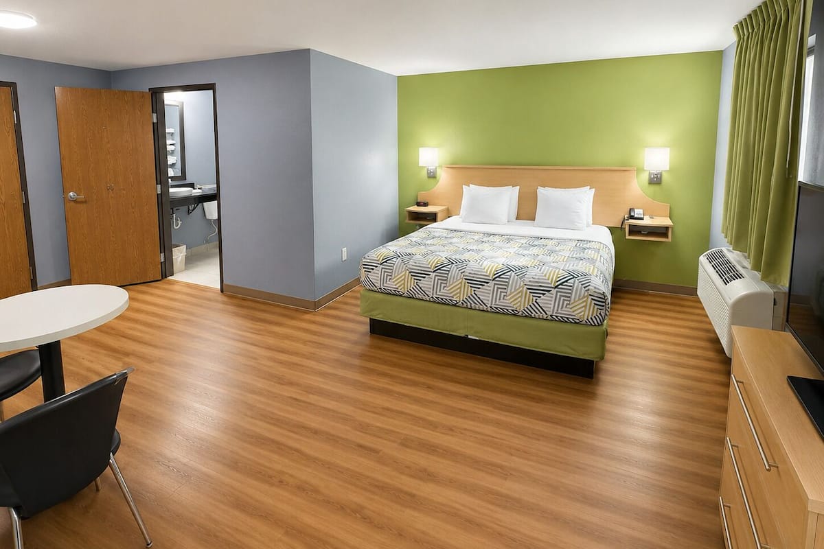 Una habitación de hotel con cama, mesitas de noche, escritorio y una silla.
