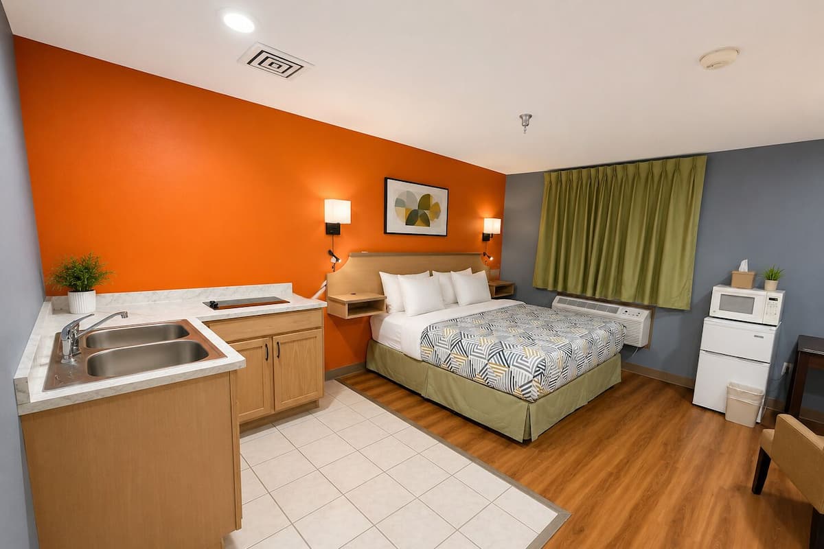 Una habitación de hotel con cama, un pequeño kitchenette, un lavamanos y un microondas.