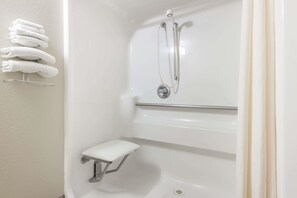 Bathroom features a walk-in shower with a wall-mounted control panel and a step stool for accessibility.