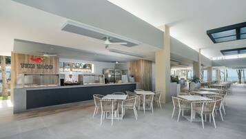 Un restaurante moderno con mostrador, sillas de mimbre blanco y vista al mar.