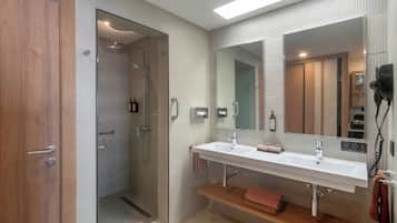 Un baño moderno con ducha a nivel, lavamanos doble y un espejo grande.