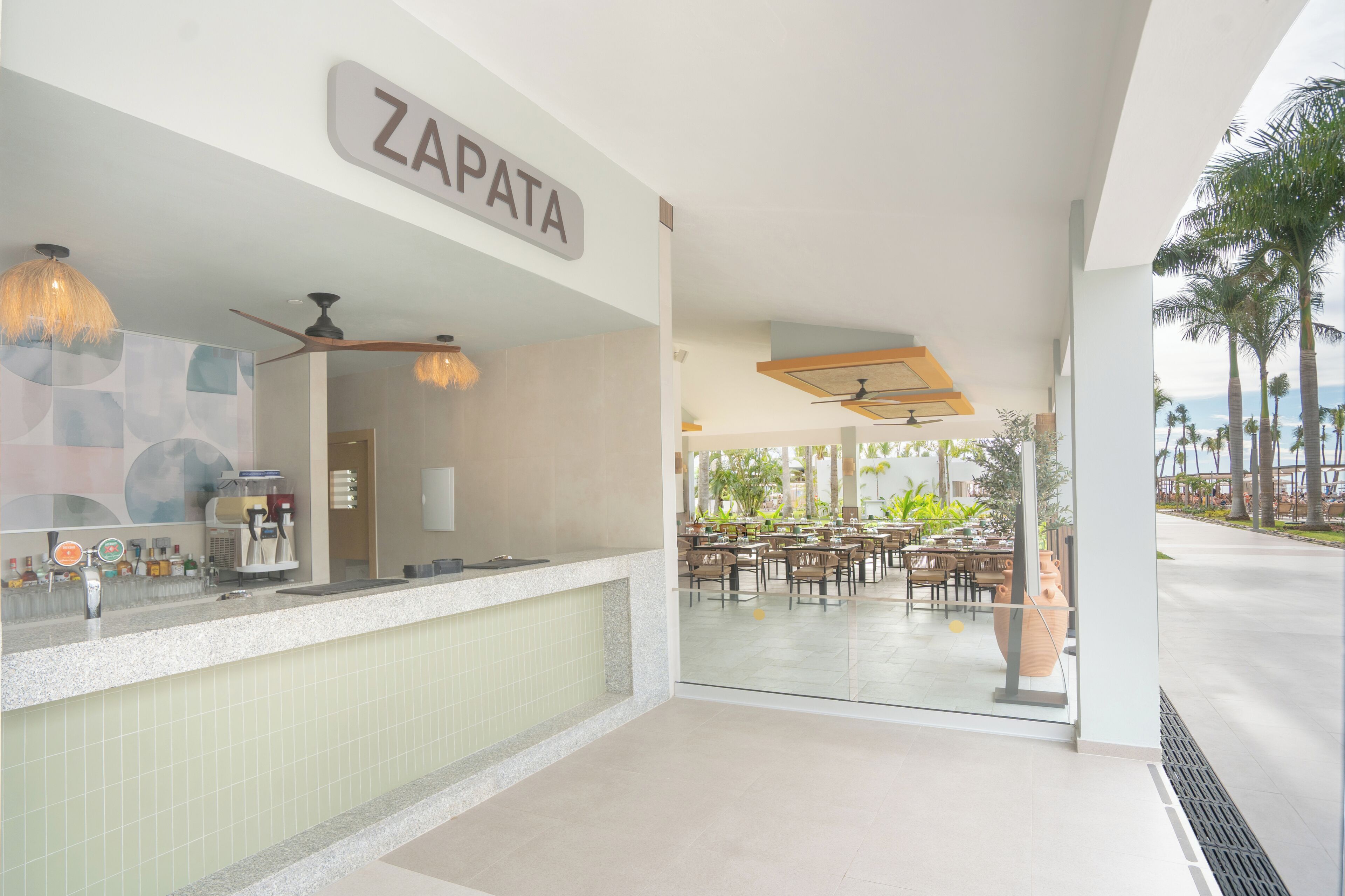 Ein Restaurant namens ZAPATA mit einer Theke, Deckenventilatoren und Blick auf den Außenbereich.